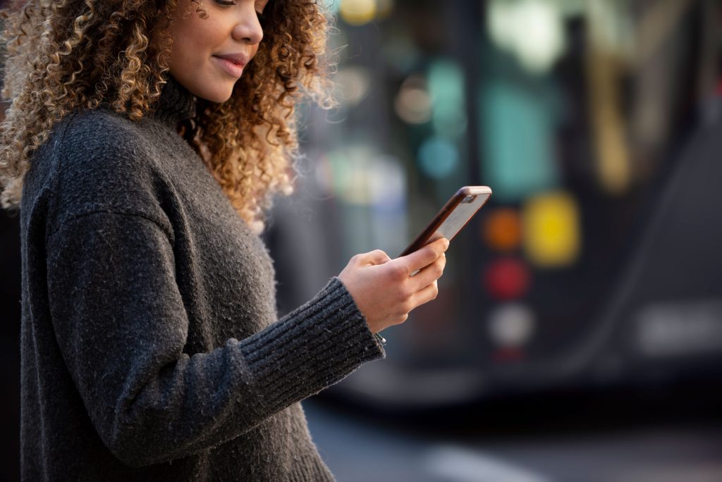 young woman using her smartphone city web