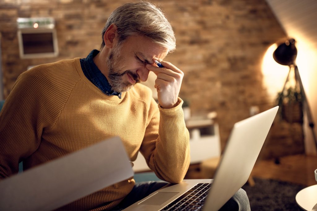 mid adult businessman having headache while working late home