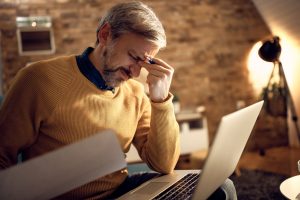 mid adult businessman having headache while working late home